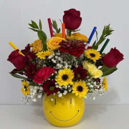 Mixed bouquet in a yellow smiley-face vase with red roses and yellow daisies