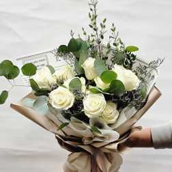 Bouquet of white roses with eucalyptus in tan wrapping