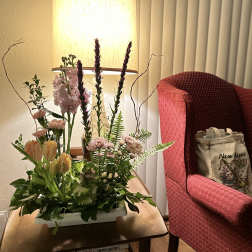 Mixed floral arrangement in a white rectangular container on a table