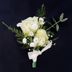 White rose boutonniere with small white filler flowers and a ribbon tie