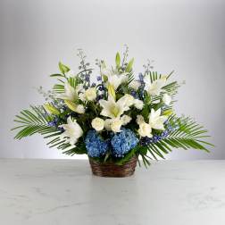 White lilies and blue hydrangeas in a woven basket