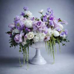 Lavender and white floral arrangement in a white pedestal vase