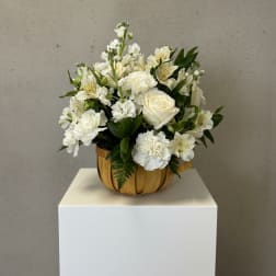 White floral arrangement in a wooden bowl on a pedestal