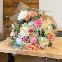 Bouquet of pink and white roses with white chrysanthemums wrapped in clear paper