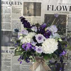 Lavender and white bouquet in a white vase with a burlap bow