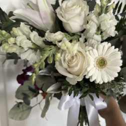 White bouquet with roses, lilies, and a gerbera daisy tied with a satin ribbon
