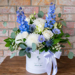 White and blue mixed bouquet in a white hat box with ribbon