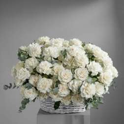 White rose arrangement in a white wicker basket with eucalyptus accents
