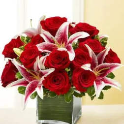Red roses and pink lilies arranged in a square glass vase