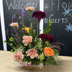 Mixed floral arrangement in a wooden box with peach, orange, and burgundy blooms