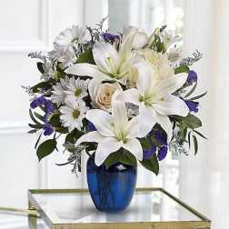 White lilies and daisies in a blue glass vase