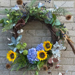 Floral wreath with sunflowers and blue hydrangeas on a twig base