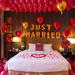 Bedroom decorated with red and gold heart balloons and a "Just Married" balloon sign