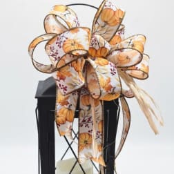 Black lantern with a large pumpkin-pattern ribbon bow and candle inside