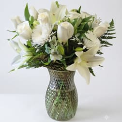 White lilies and roses arranged in a textured glass vase