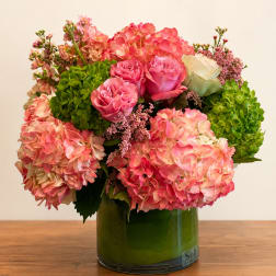 Pink roses and hydrangeas arranged in a green glass vase