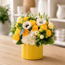 Yellow and white flower arrangement in a yellow vase