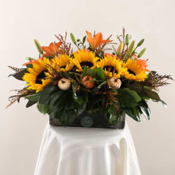 Sunflowers and orange lilies arranged in a rectangular vase
