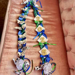 Two ribbon garlands with paper flowers and glitter numbers on a pink couch