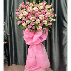 Pink and white floral standing spray with a large pink bow