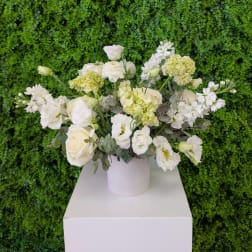White and pale green floral arrangement in a white vase