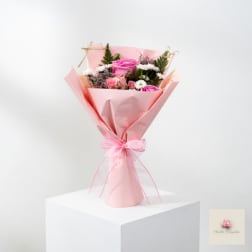 Pink bouquet with roses and small white flowers wrapped in pink paper