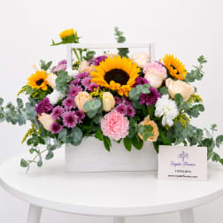 Mixed bouquet in a white wooden box with sunflowers, roses, and purple blooms