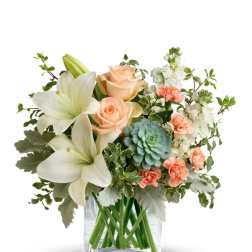 Peach roses and white lilies in a clear glass vase