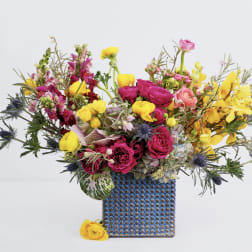 Bright mixed bouquet in a blue patterned vase with yellow and pink flowers