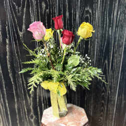 Bouquet of pink, red, and yellow roses in a glass vase with a yellow ribbon
