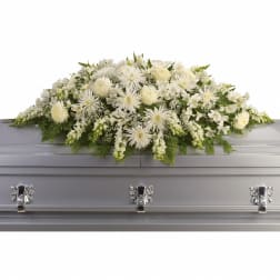 White floral casket spray with mixed blooms on a silver casket