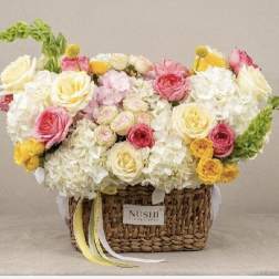 Basket arrangement of white and pink roses with yellow accents