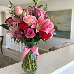 Pink mixed bouquet in a clear glass vase with a pink ribbon