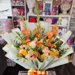 Bouquet of orange and peach roses with tall orange blooms wrapped in pale paper