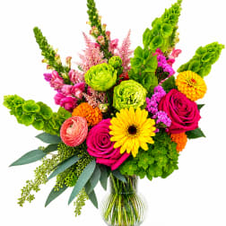 Bright mixed bouquet in a clear glass vase with roses, gerbera daisies, and green blooms