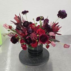 Deep red and burgundy bouquet in a black vase