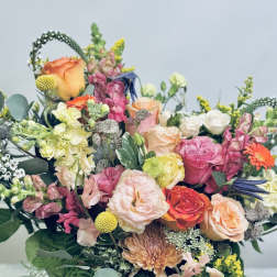 Mixed bouquet of roses, snapdragons, and chrysanthemums in a white vase