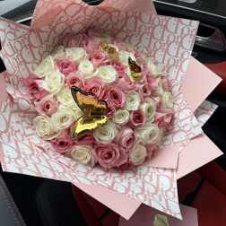Pink and white rose bouquet wrapped in patterned pink paper with butterfly picks