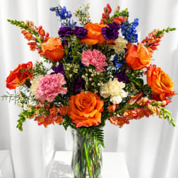 Colorful bouquet of roses, carnations, and snapdragons in a clear glass vase