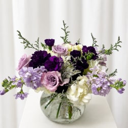 Purple and lavender flowers arranged in a clear glass vase