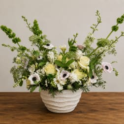 White and pale yellow floral arrangement in a textured ceramic vase