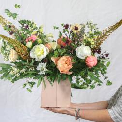 Mixed bouquet in a pink box with peach, white, and burgundy blooms