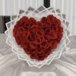 Heart-shaped bouquet of red roses wrapped in white paper