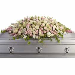 Pastel pink and ivory rose casket spray draped across a silver casket
