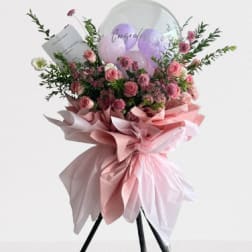 Pink rose bouquet with balloons and a card on a stand