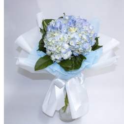 Blue and white hydrangea bouquet wrapped in white paper with a ribbon
