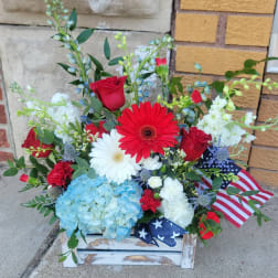 Mixed red, white, and blue floral arrangement in a rustic wooden box