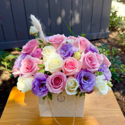 Pink, white, and purple roses arranged in a white box