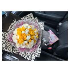 Bouquet of yellow and white roses wrapped in patterned paper