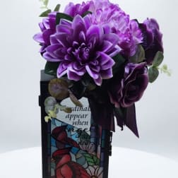 Purple floral arrangement in a stained-glass style vase